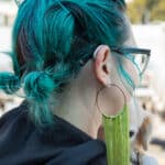 Back view of a female with green hair wearing silver hearing technology.