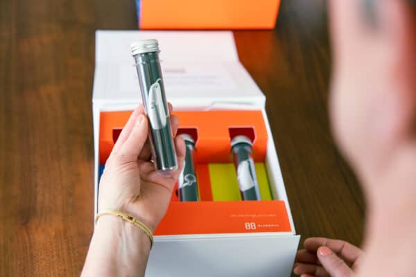 Woman holding a set of trial devices from a vibrantly colored at home hearing trial experience box.