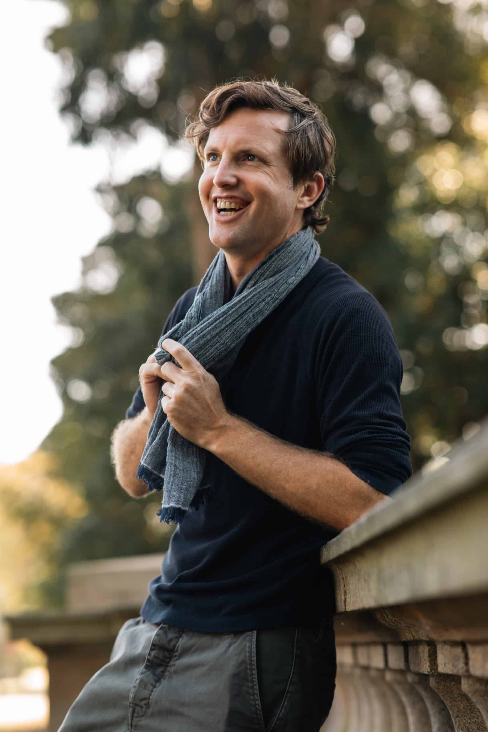 A man wearing a shirt and scarf is seen laughing.