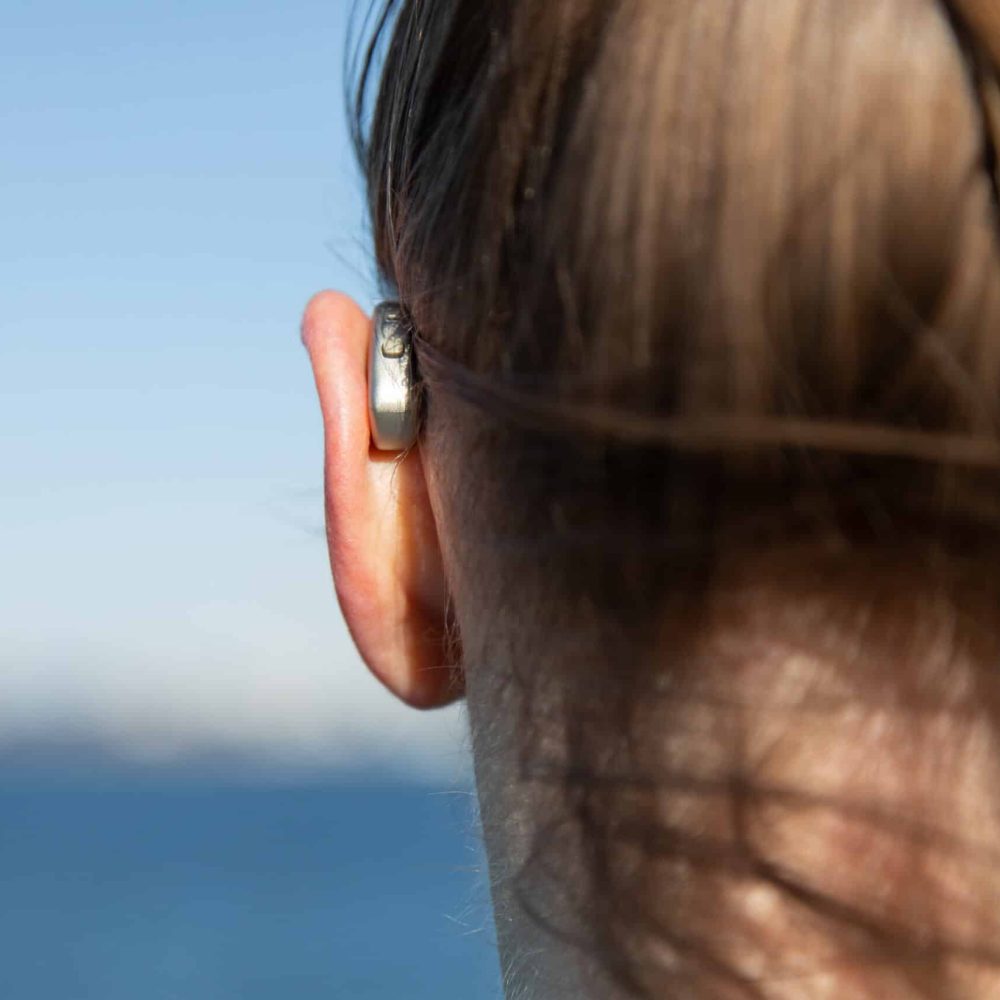 woman staring at water with hearing aid.
