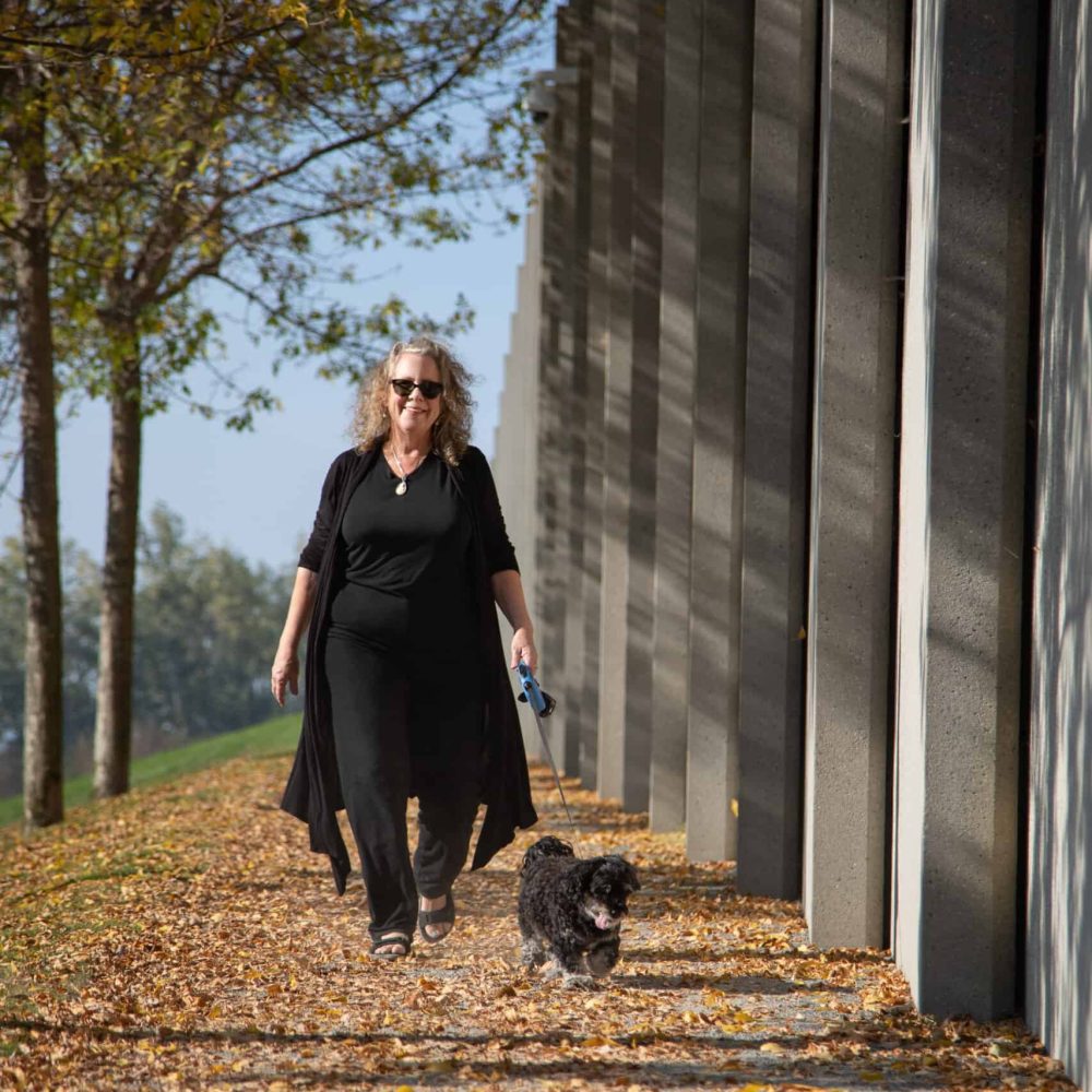 woman walking dog in the sun looking happy and excited.